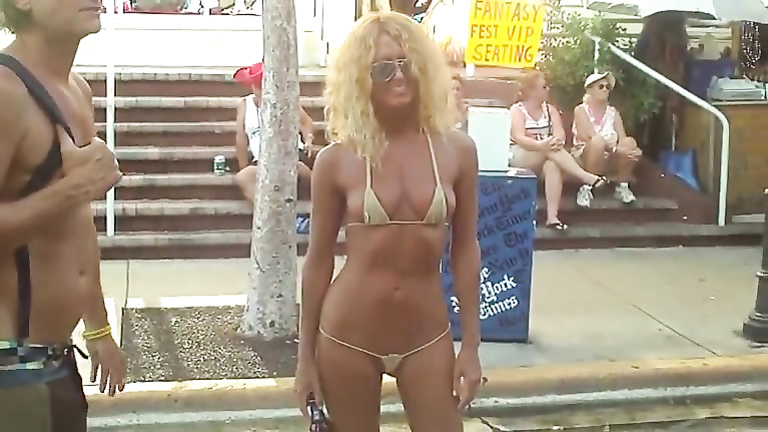 Babe in a micro bikini poses on the street voyeurstyle image